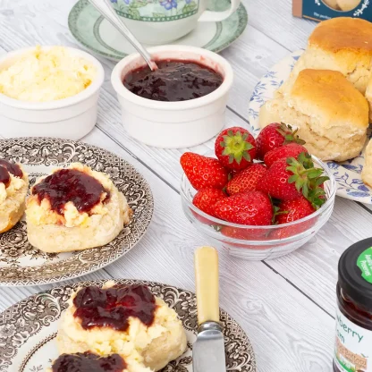 Bowl of bright red fresh strawberries surrounded by Devon cream teas