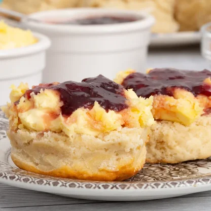 Freshly baked scones topped with langage cream and strawberry jam